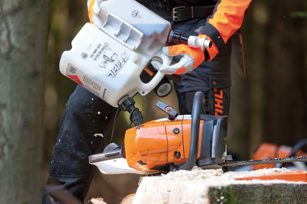 A STIHL MS 441 chainsaw being filled from a combination canister