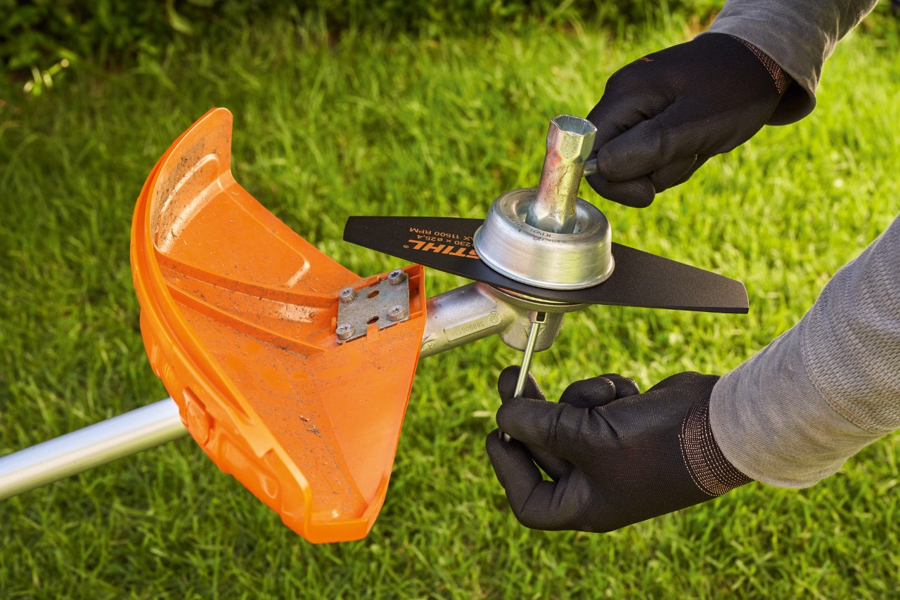 To change the cutting tool of a motor scythe, the shaft is blocked with an angular screwdriver