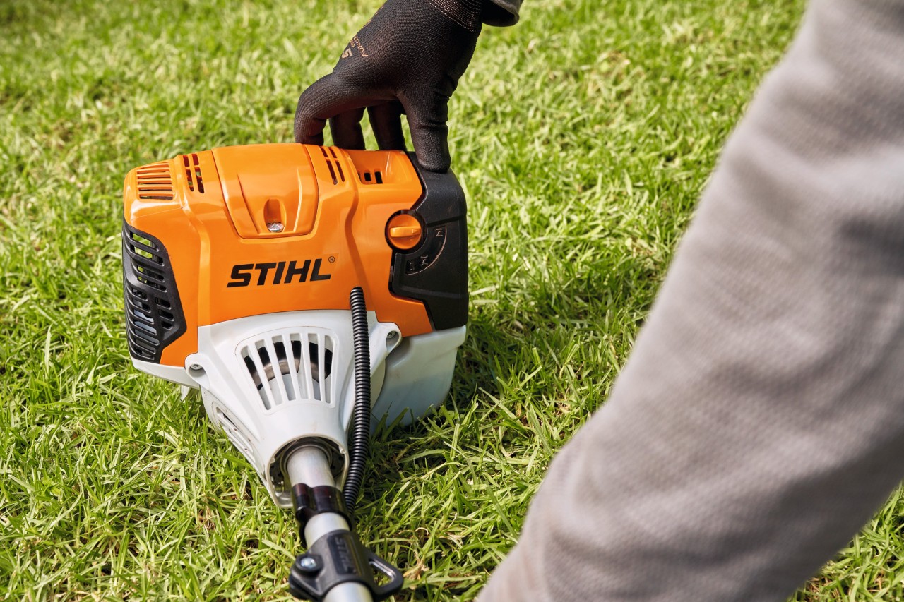 A man pressing a STIHL FS 91 petrol brushcutter firmly onto the ground