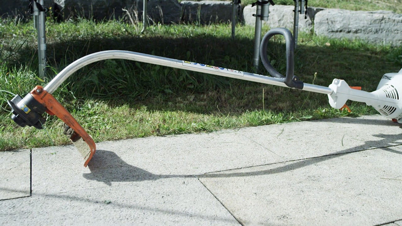 A man placing a STIHL FS 56 petrol brushcutter on the ground to start it