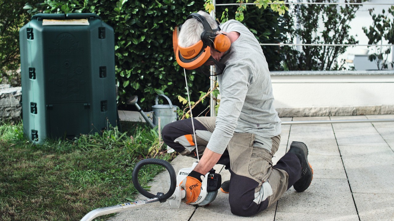 Person wearing protective clothing pulling the starter cord of the STIHL FS 38 petrol brushcutter again