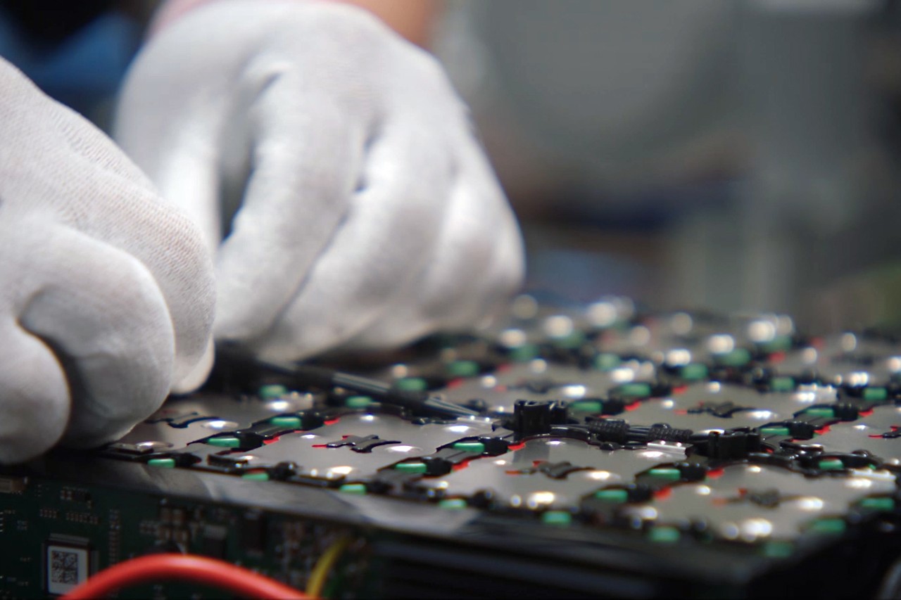 Close-up of a person wearing work gloves mounting sensors on a battery