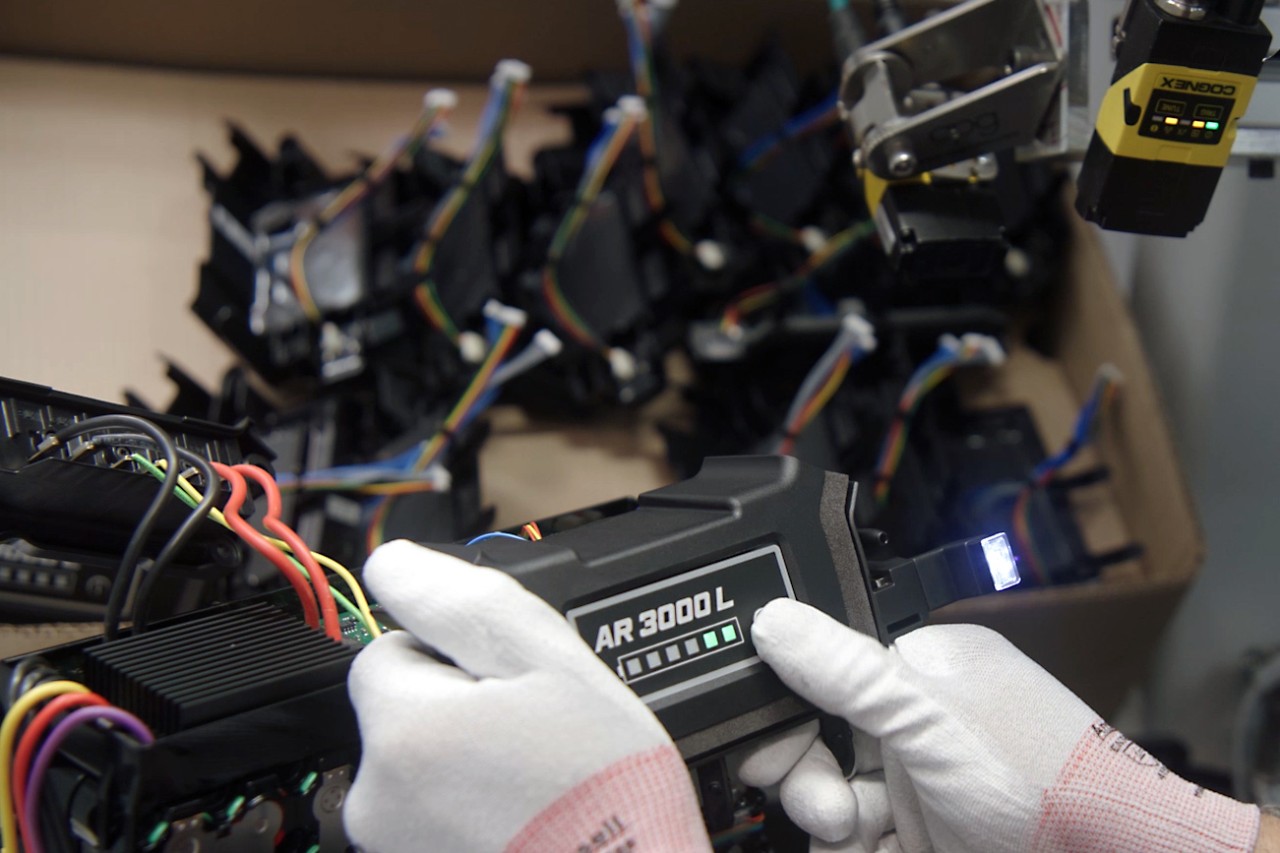 A person wearing gloves looking at the green charge level indicator of a STIHL AR 3000 L backpack battery