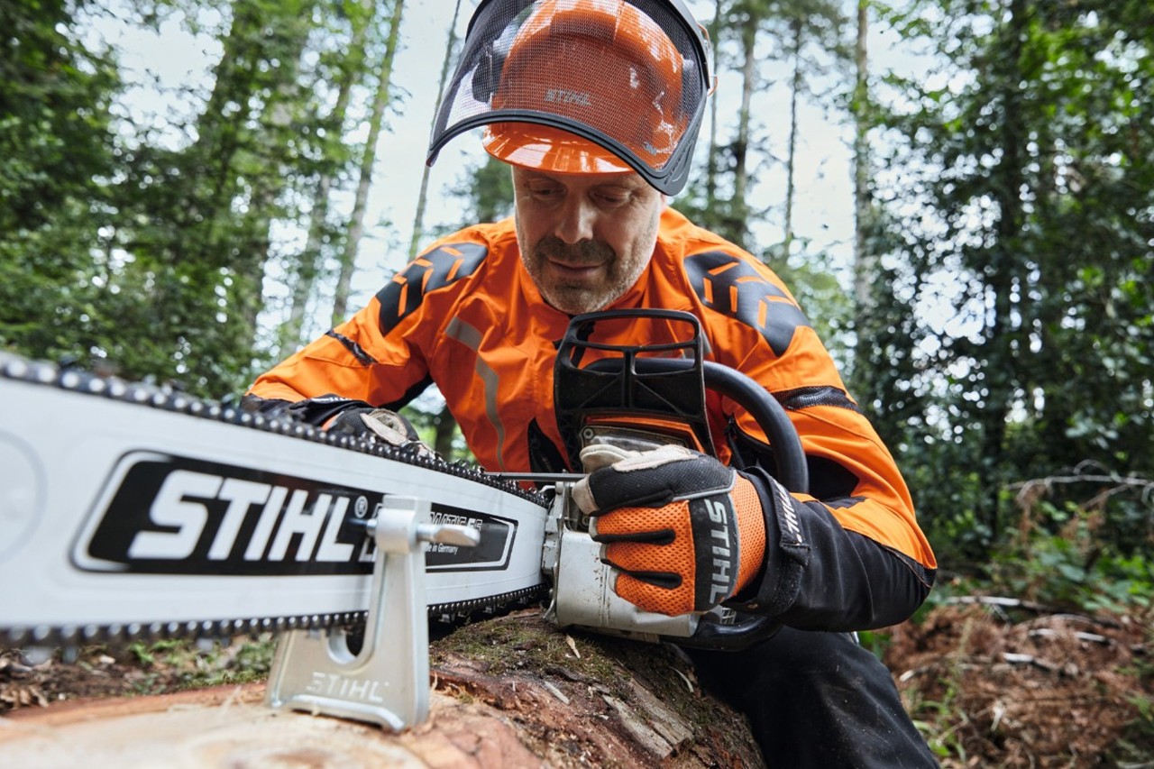 A man wearing protective equipment working with a STIHL chainsaw in a forest