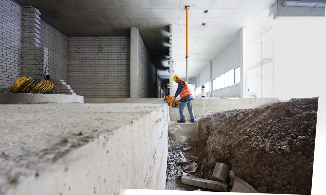 A man with a STIHL TS 500i petrol-driven cut-off machine cutting a steel bolt on a construction site