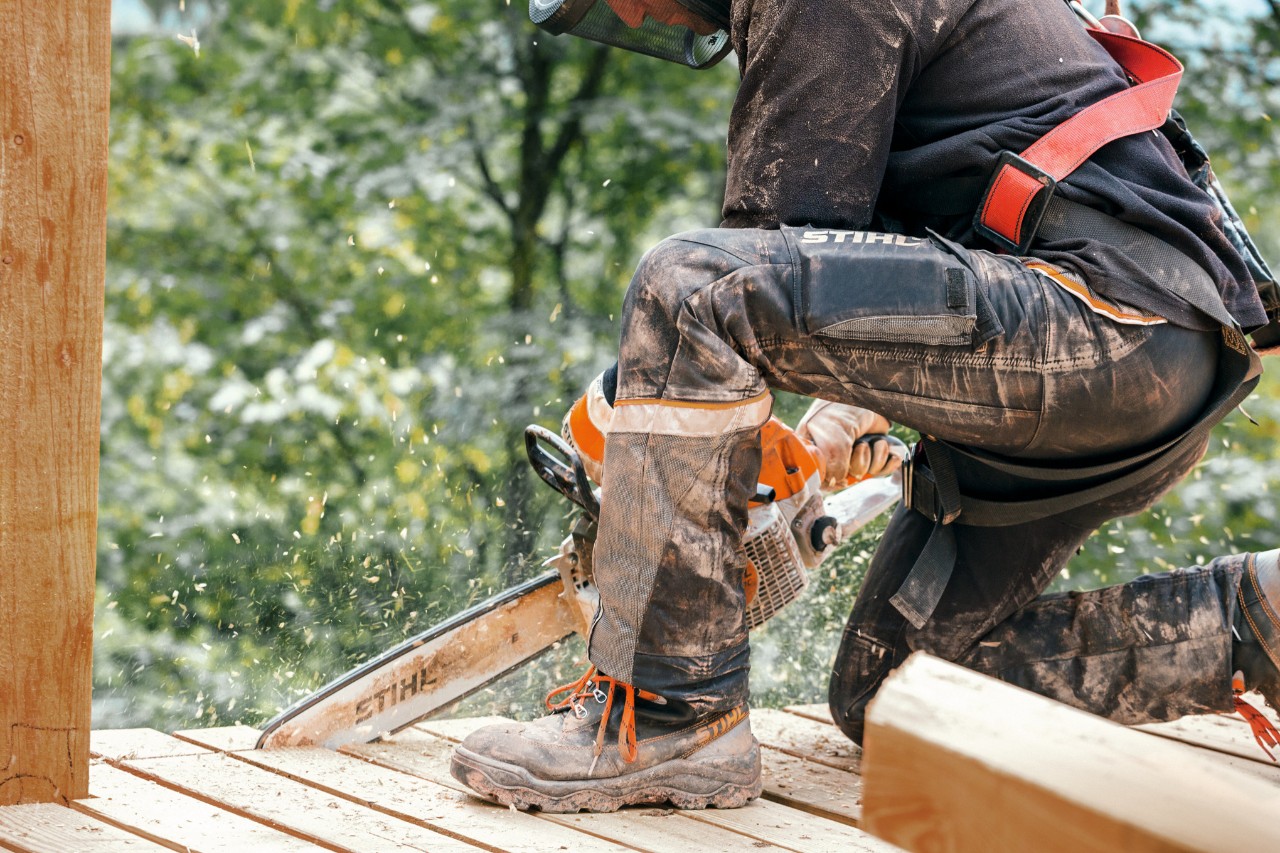 Forestry worker wearing STIHL protective clothing with Dynamic Vent trousers (cut protection class 1) sawing wood with a STIHL chainsaw