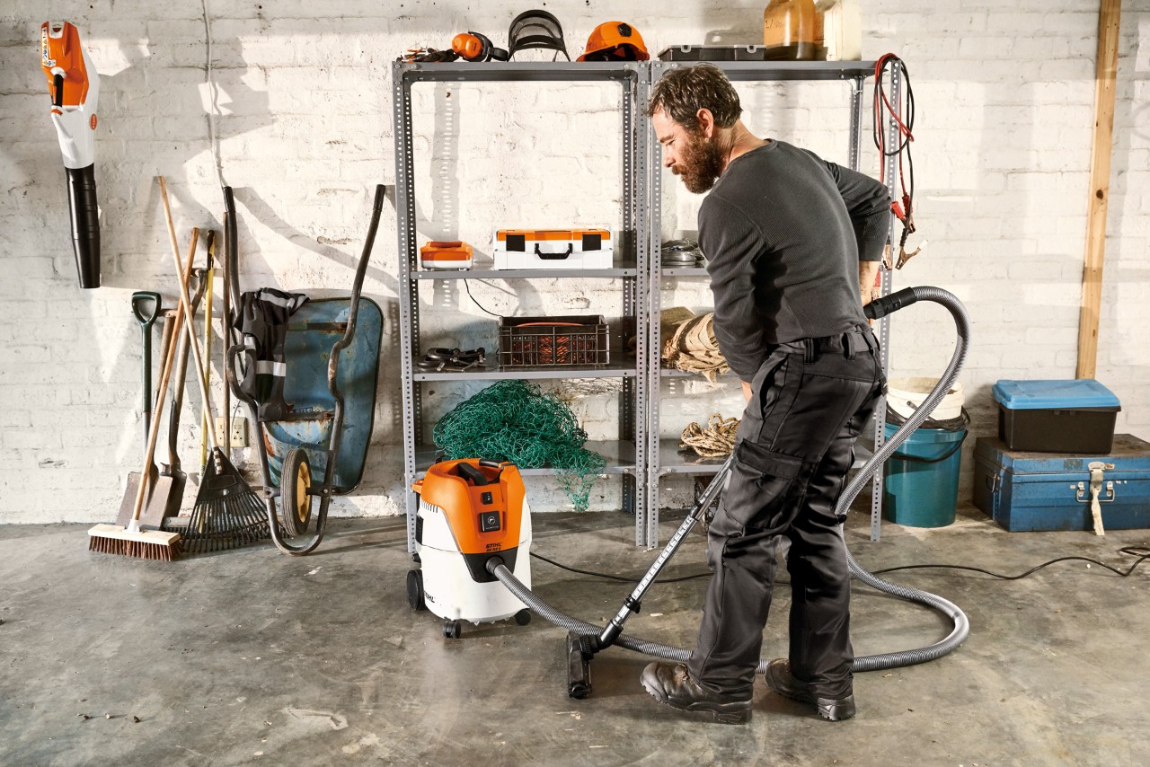 Man vacuuming the floor of a garage using a STIHL SE 62 E wet and dry vacuum cleaner