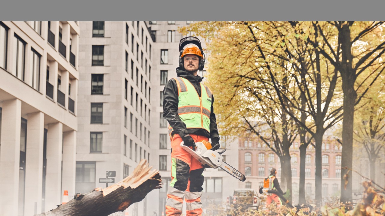 A man standing in front of a tree with a STIHL chainsaw